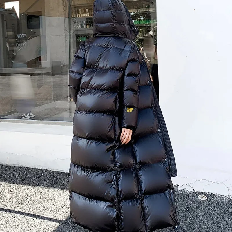 Person wearing a long black puffer coat standing on a street.