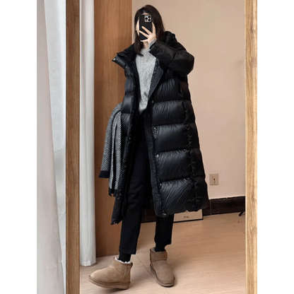 Person wearing a long black puffer coat in a room.