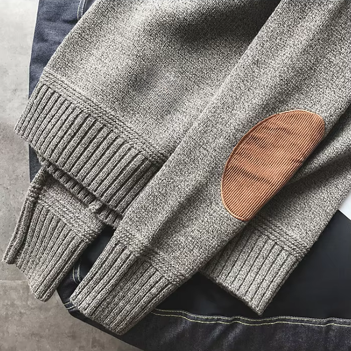 Gray sweater with a brown leather patch on a gray surface