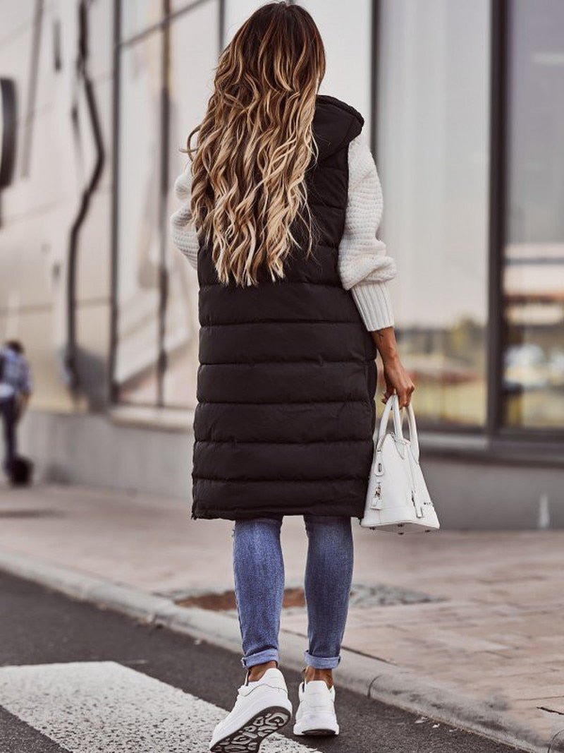 Person wearing a long black puffer vest on a city street.
