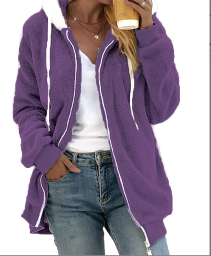Person wearing a purple fleece jacket with white trim, holding a coffee cup.