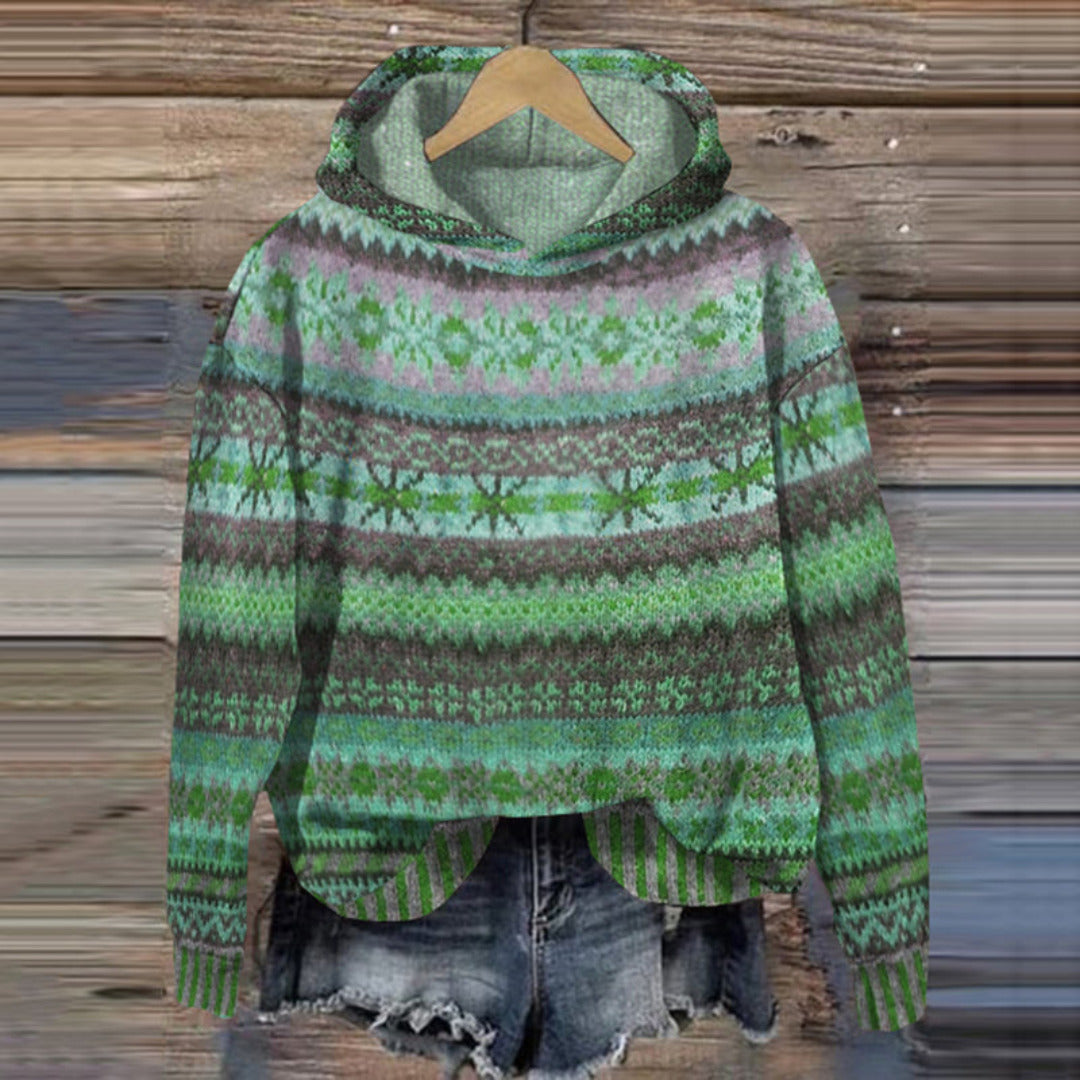 Green patterned hoodie on a wooden hanger against a wooden background
