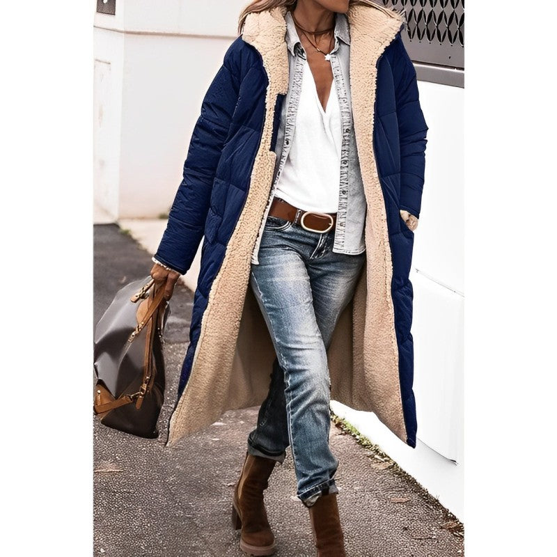 Person wearing a long navy coat with a beige fur-lined hood, blue jeans, and brown boots.