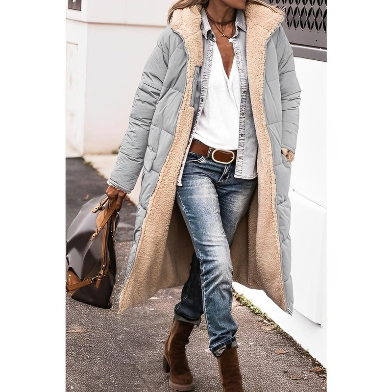 Person wearing a long gray coat with a beige fur-lined hood, blue jeans, and brown boots.