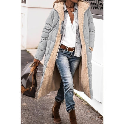 Person wearing a long gray coat with a beige fur-lined hood, blue jeans, and brown boots.