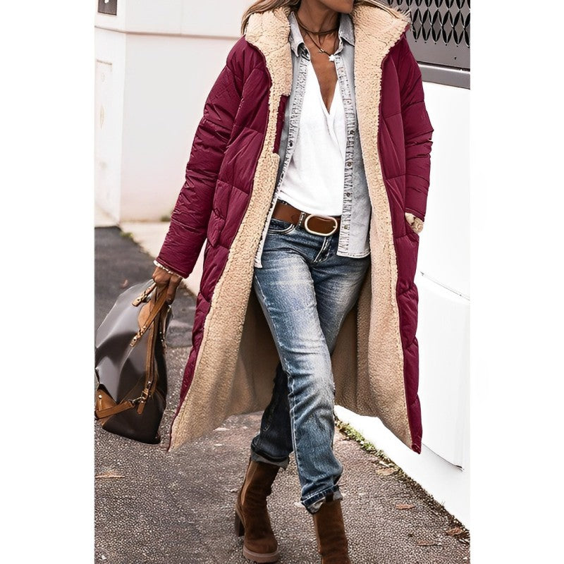Person wearing a burgundy puffer coat with beige fur lining, blue jeans, and brown boots.