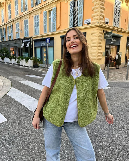 Woman wearing a green vest and white shirt on a city street