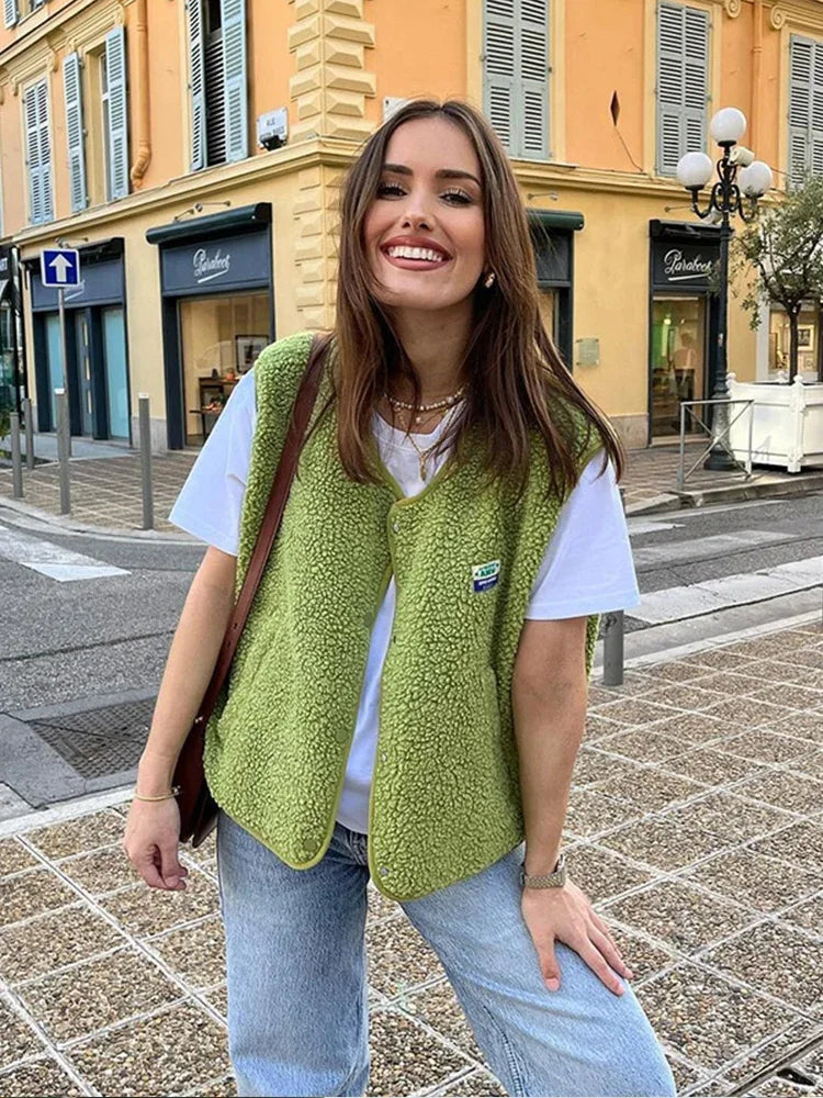 Woman wearing a green vest and white shirt on a city street