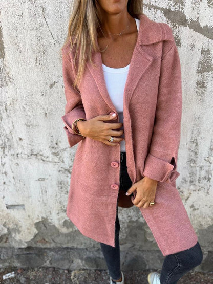 Person wearing a pink coat against a textured wall.