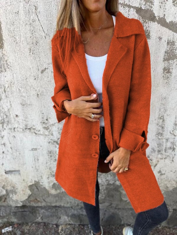 Person wearing an orange coat against a textured wall background