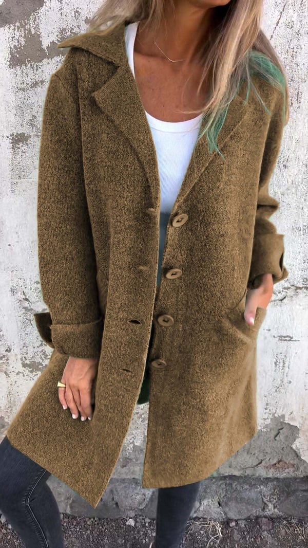 Person wearing a brown coat against a textured wall.