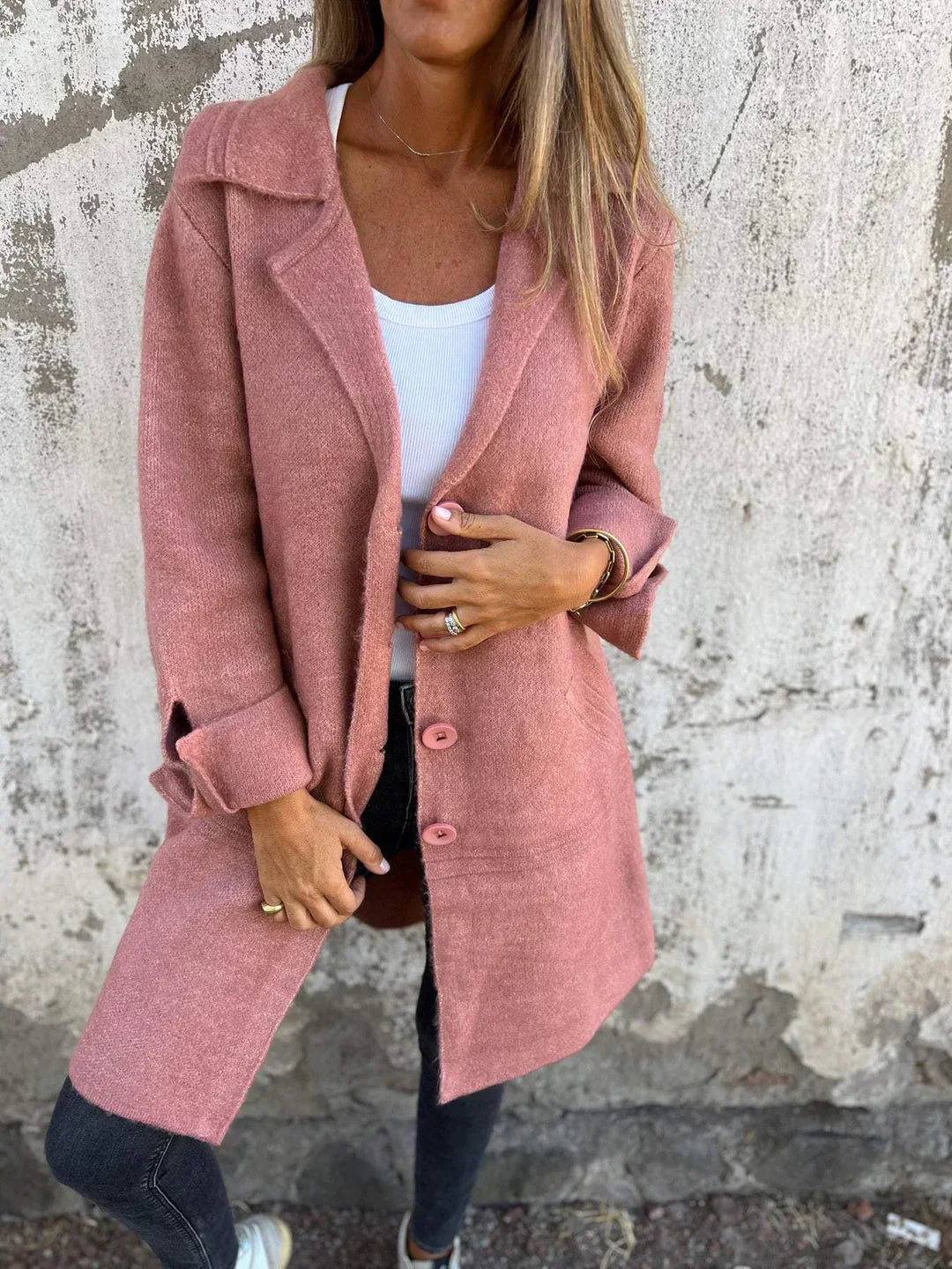 Person wearing a pink coat against a textured wall.