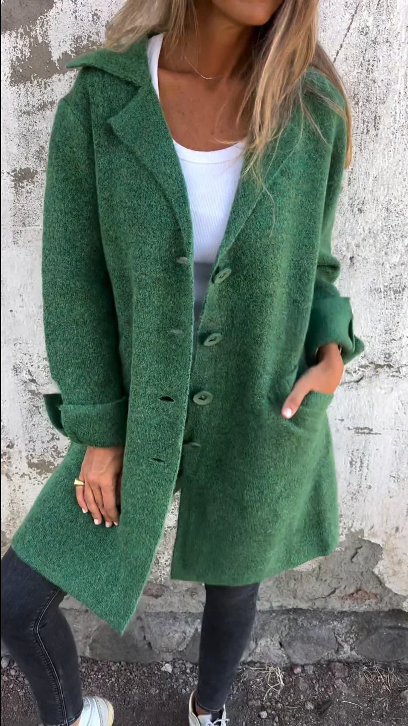 Person wearing a green coat against a textured wall.