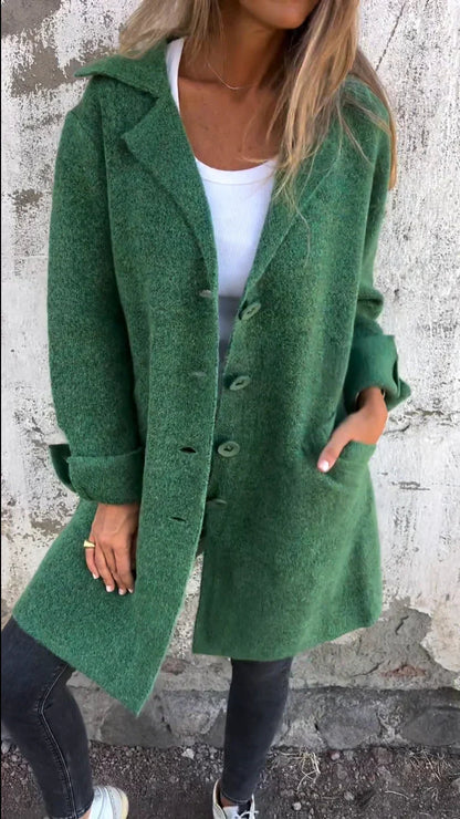 Person wearing a green coat against a textured wall.