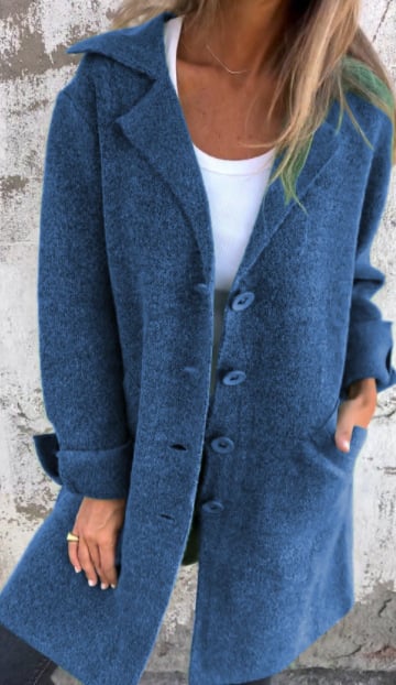 Blue coat worn by a person against a gray wall