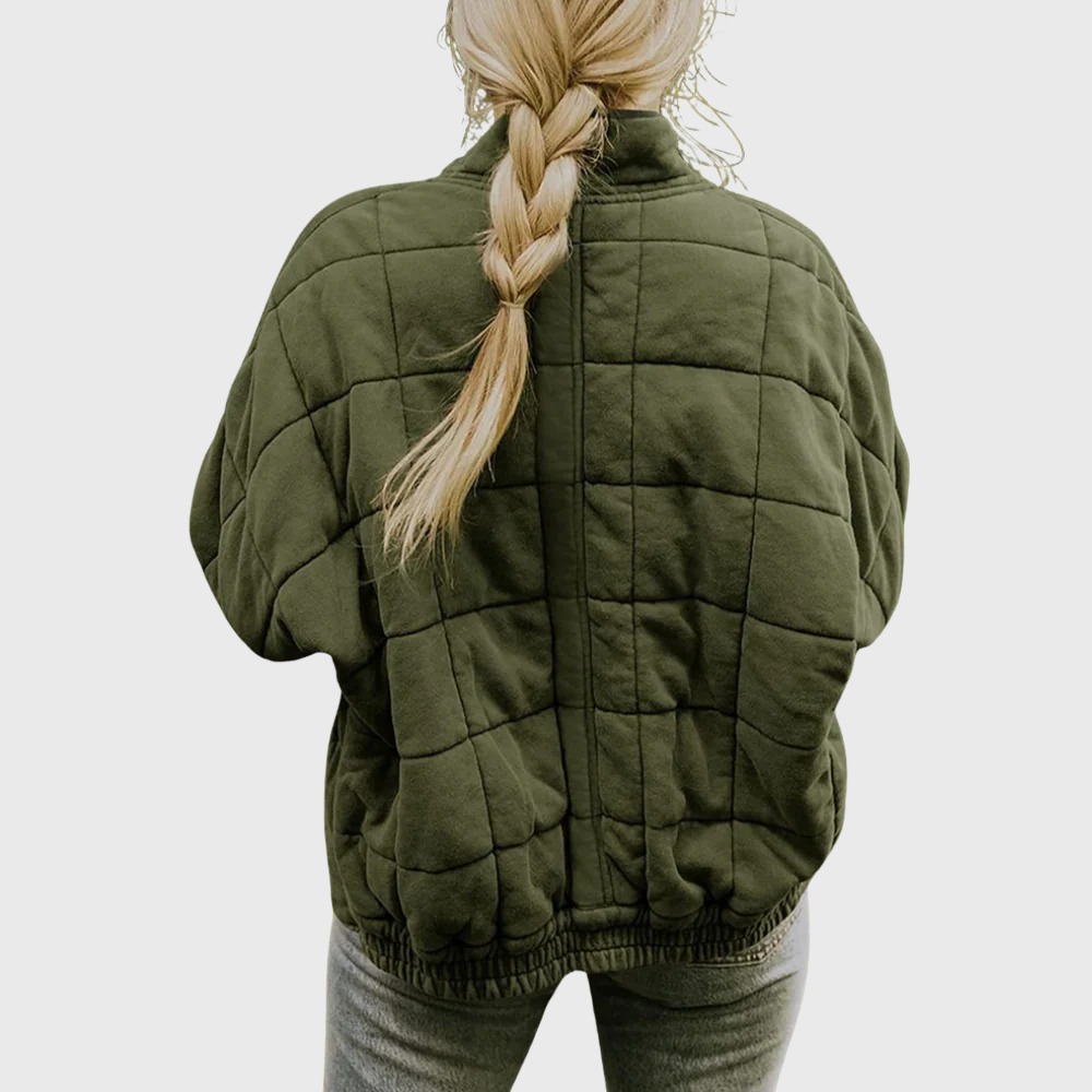 Person wearing a green quilted jacket with a plain background
