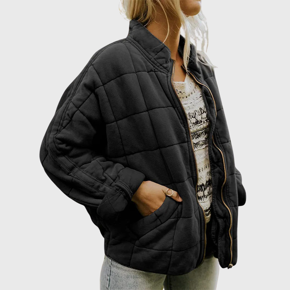 Person wearing a black quilted jacket on a plain background