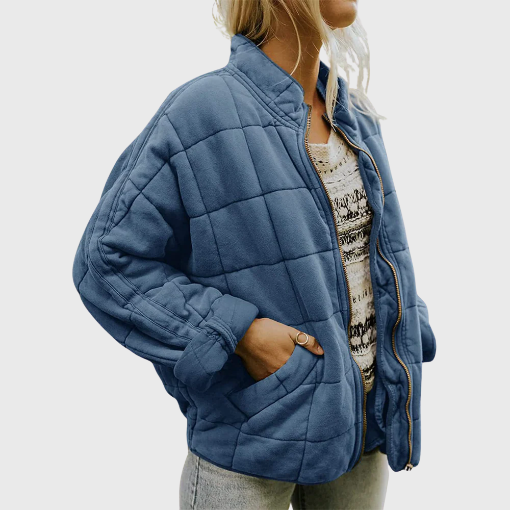 Person wearing a blue quilted jacket on a plain background