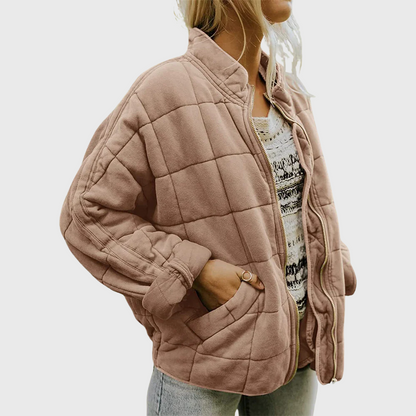 Person wearing a quilted pink jacket with a neutral background