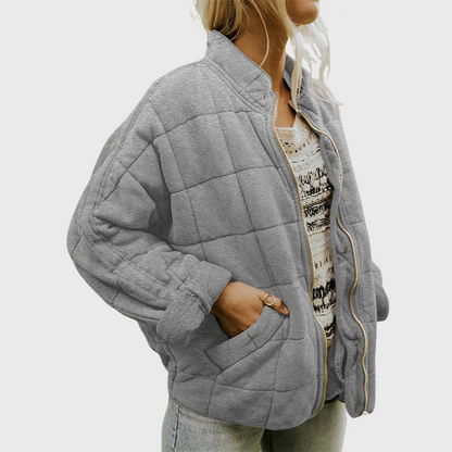 Person wearing a gray quilted jacket on a white background