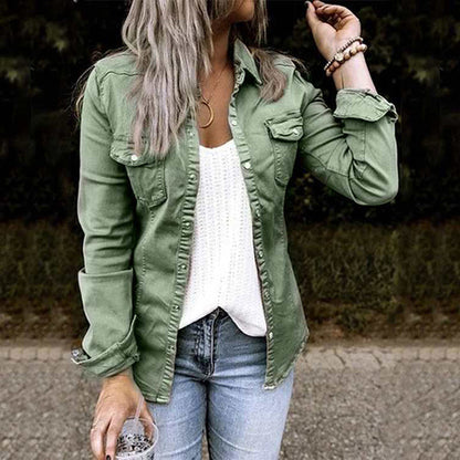 Person wearing a green jacket, white top, and blue jeans outdoors.