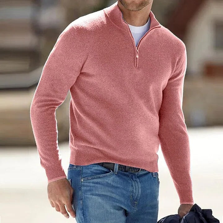 Man wearing a pink long-sleeve shirt with a quarter zip and blue jeans.