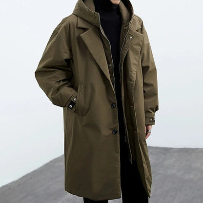 Long olive green coat worn by a person on a plain background