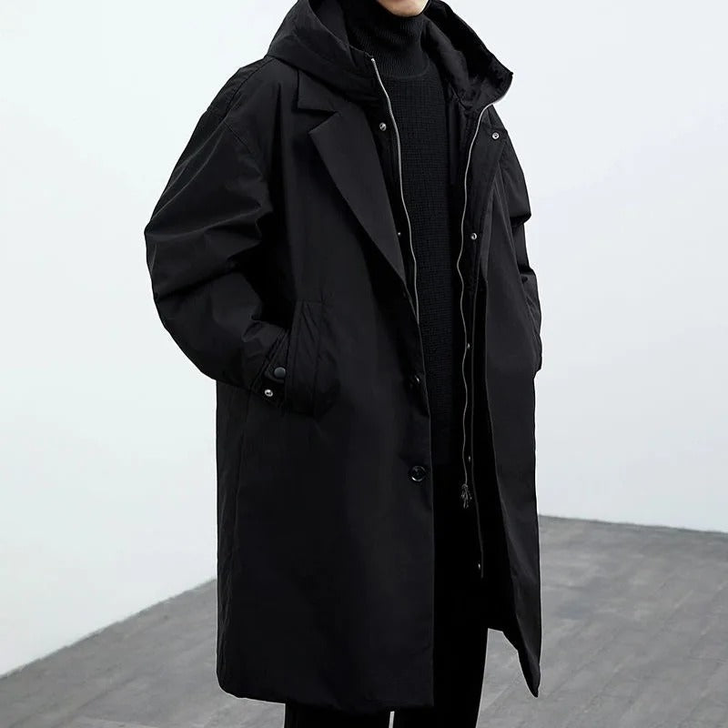 Person wearing a long black coat against a white background
