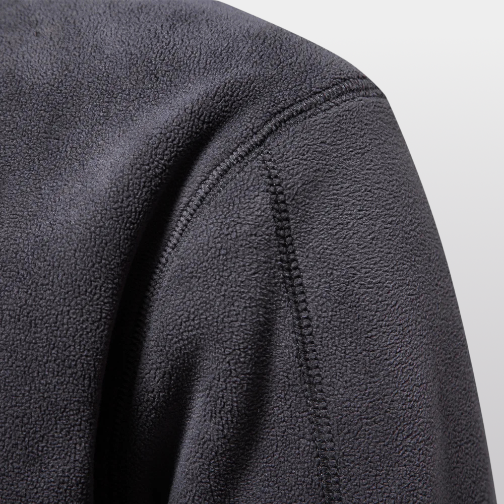 Close-up of a textured gray fleece fabric with stitching detail on a light gray background