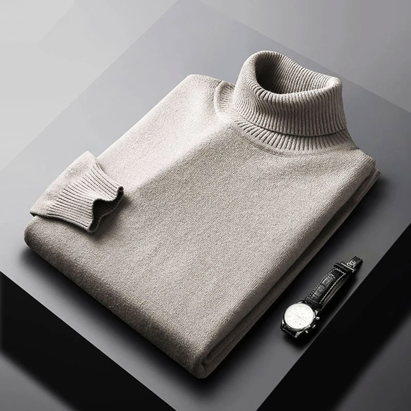 Folded gray turtleneck sweater on a dark surface with a watch beside it