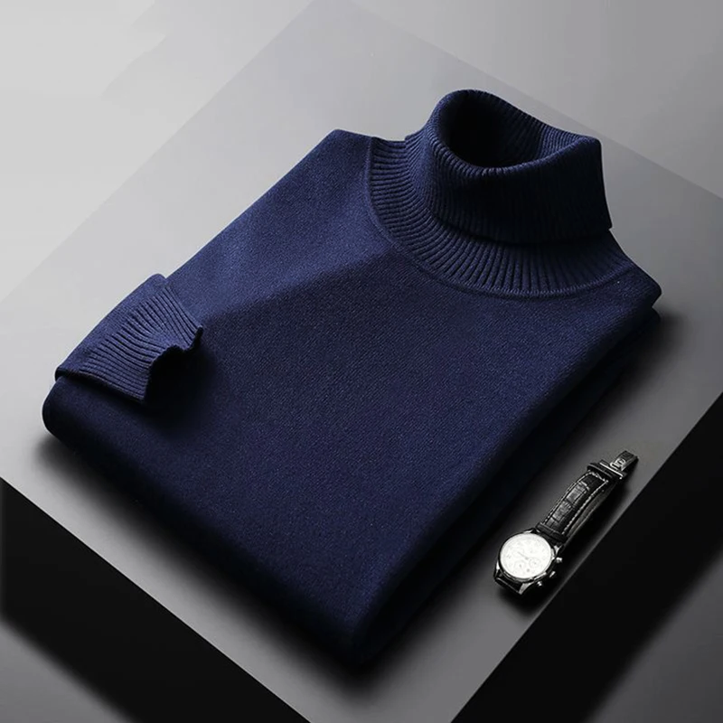 Folded navy blue turtleneck sweater on a gray surface with a watch beside it.