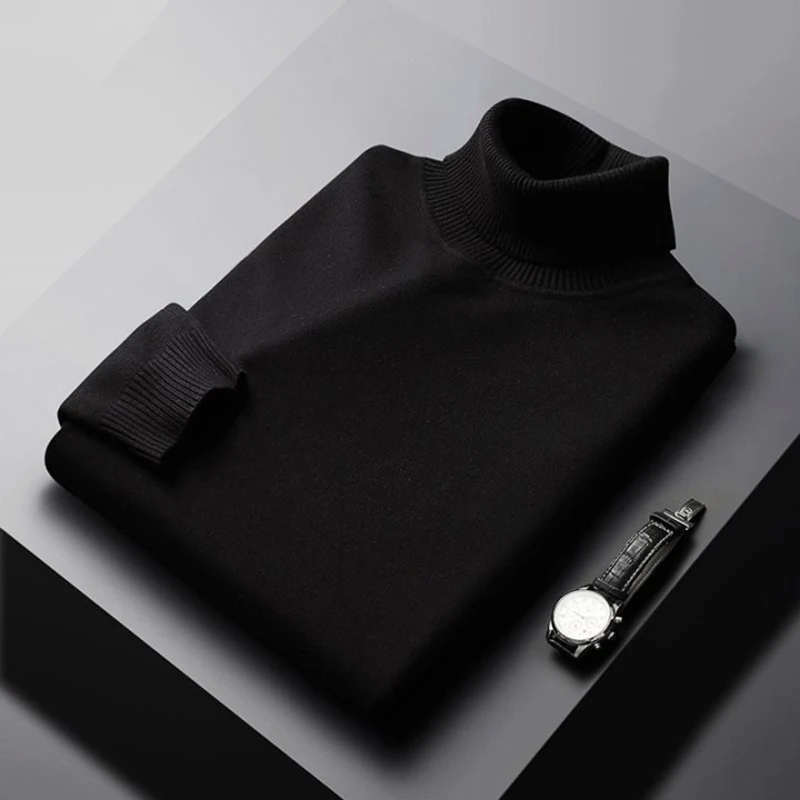 Folded black turtleneck sweater on a gray surface with a watch beside it