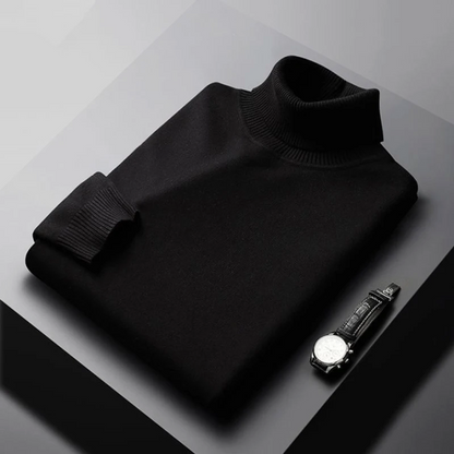 Folded black turtleneck sweater on a gray surface with a watch beside it