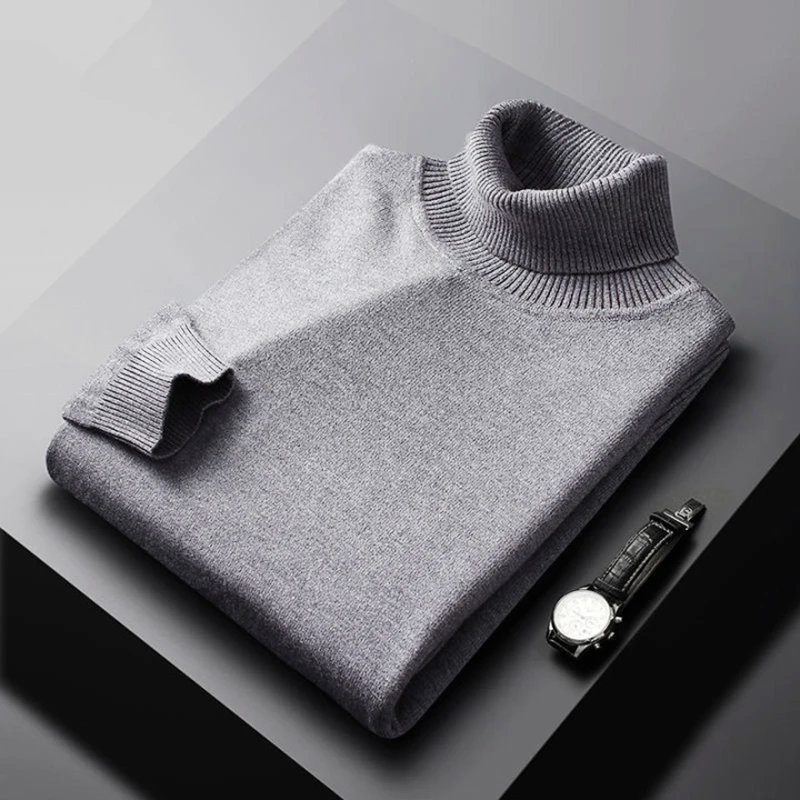 Folded gray turtleneck sweater on a dark surface with a watch.