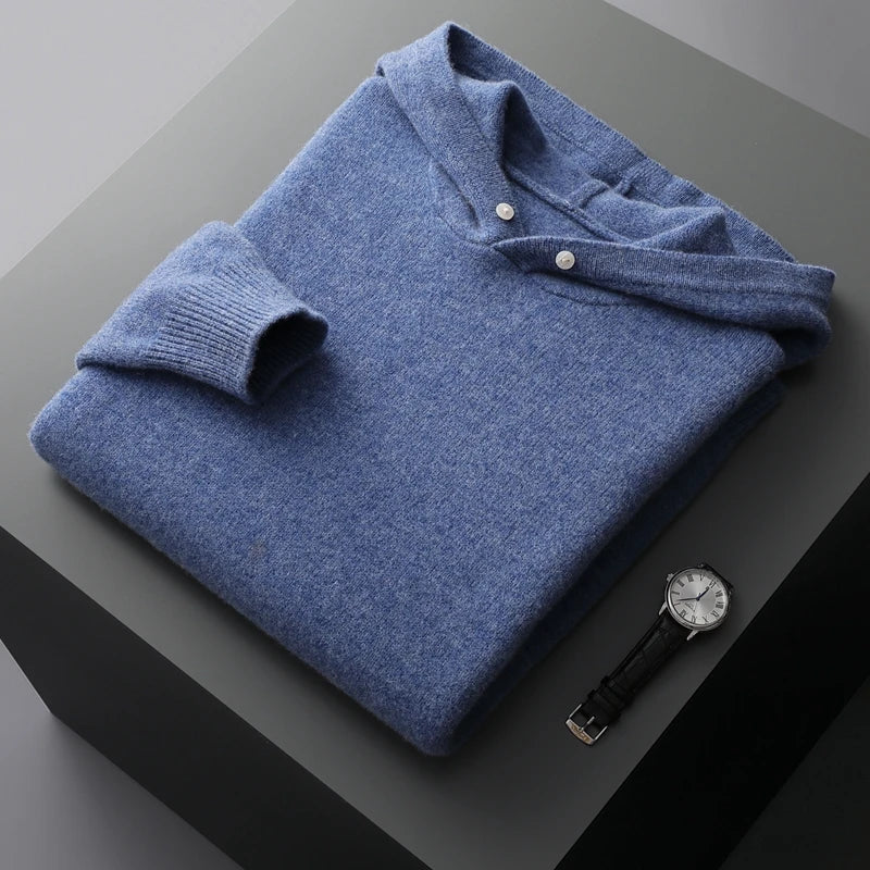 Folded blue sweater on a dark surface with a watch next to it