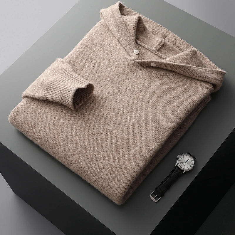 Folded beige sweater on a dark surface with a watch beside it