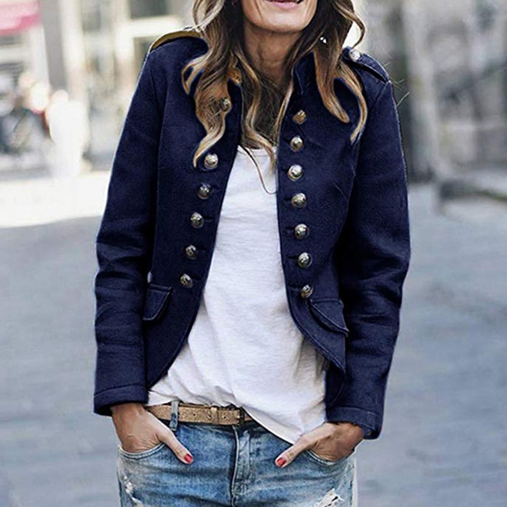 Woman wearing a navy blue peacoat with gold buttons, white shirt, and jeans outdoors.