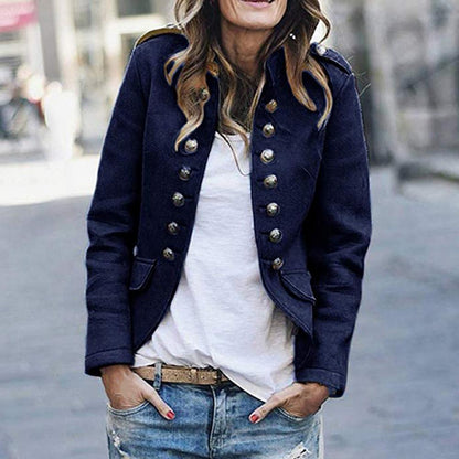 Woman wearing a navy blue peacoat with gold buttons, white shirt, and jeans outdoors.