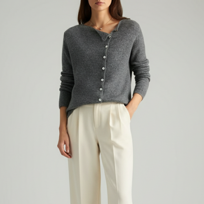 Person wearing a gray cardigan and white pants on a plain background