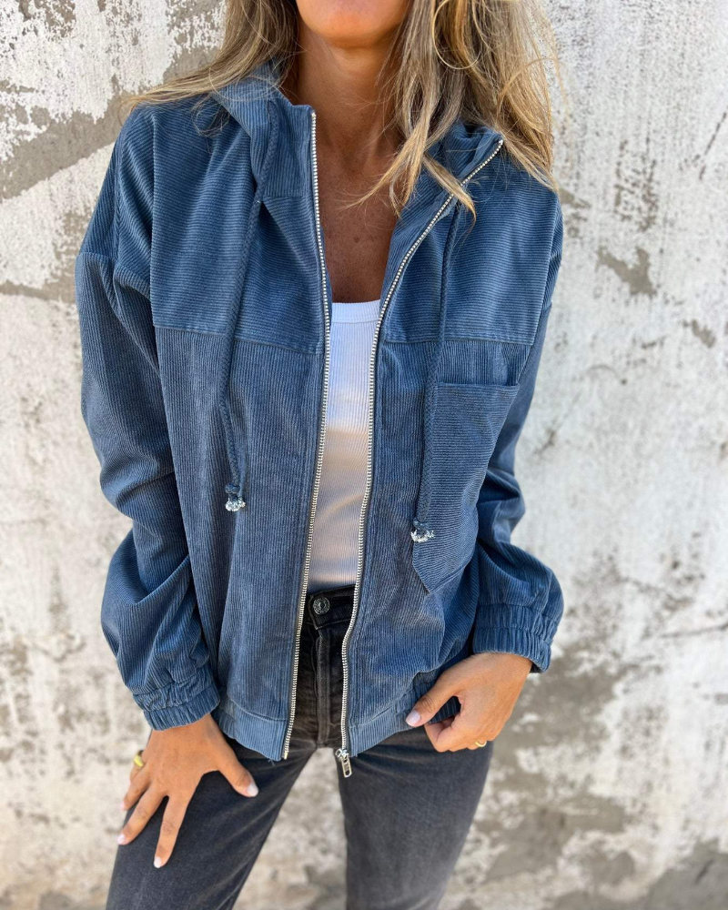 Person wearing a blue denim jacket against a textured wall.