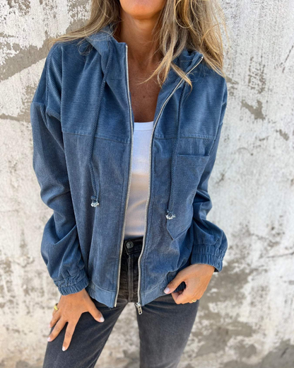 Person wearing a blue denim jacket against a textured wall.