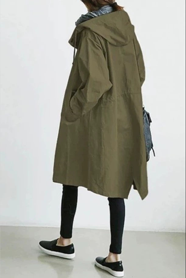 Person wearing a long olive green coat against a white background