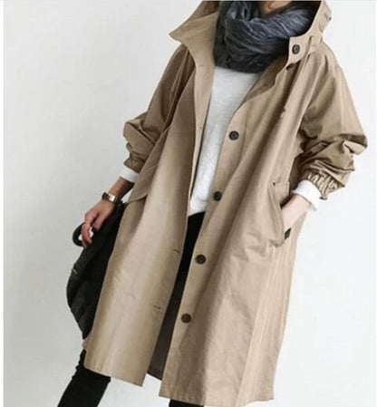 Person wearing a beige trench coat with a plain background