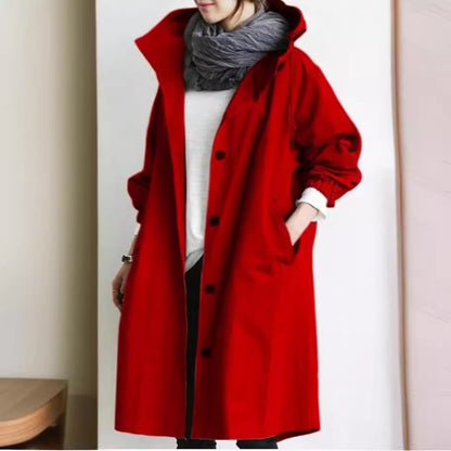 Person wearing a long red coat with a plain background