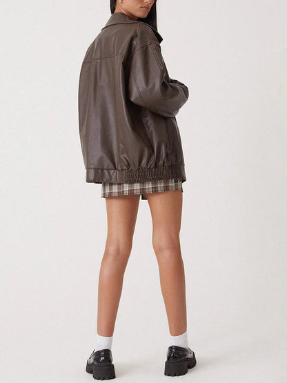 Person wearing a dark brown jacket and plaid skirt on a white background
