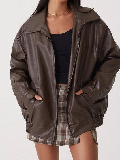 Person wearing a brown leather jacket over a black top and plaid skirt on a white background
