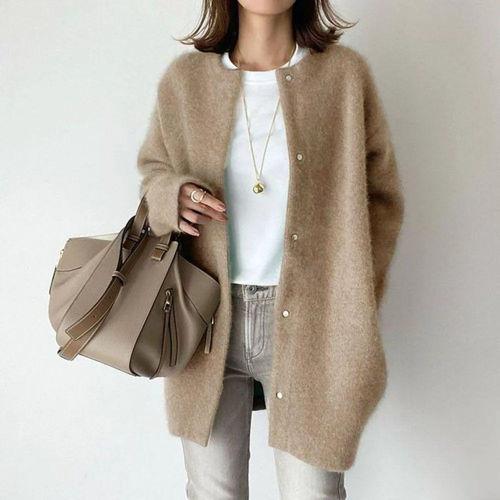 Person wearing a beige cardigan holding a matching handbag on a plain background