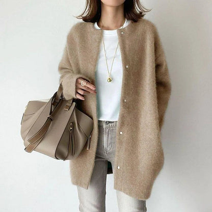Person wearing a beige cardigan holding a matching handbag on a plain background